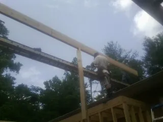 Carpenter setting a ridge beam over a new addition frame — Ice Dam Removal by Roofing Brothers in Blachly