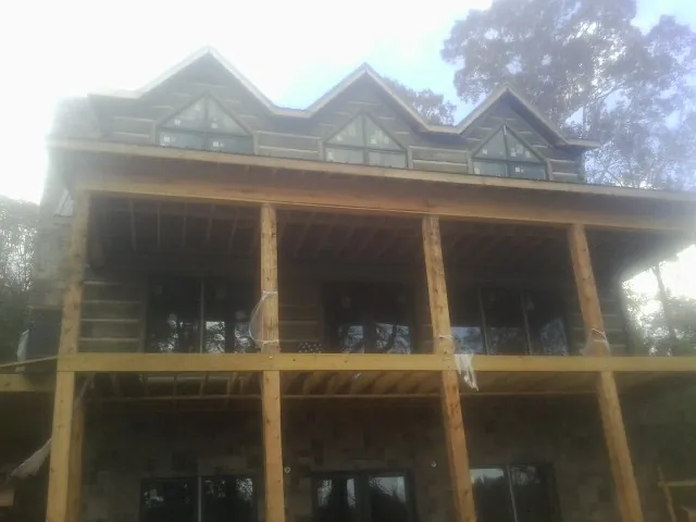 Dormers and porch framing on a large log home under construction — Roof Coating work by our crew in Blachly