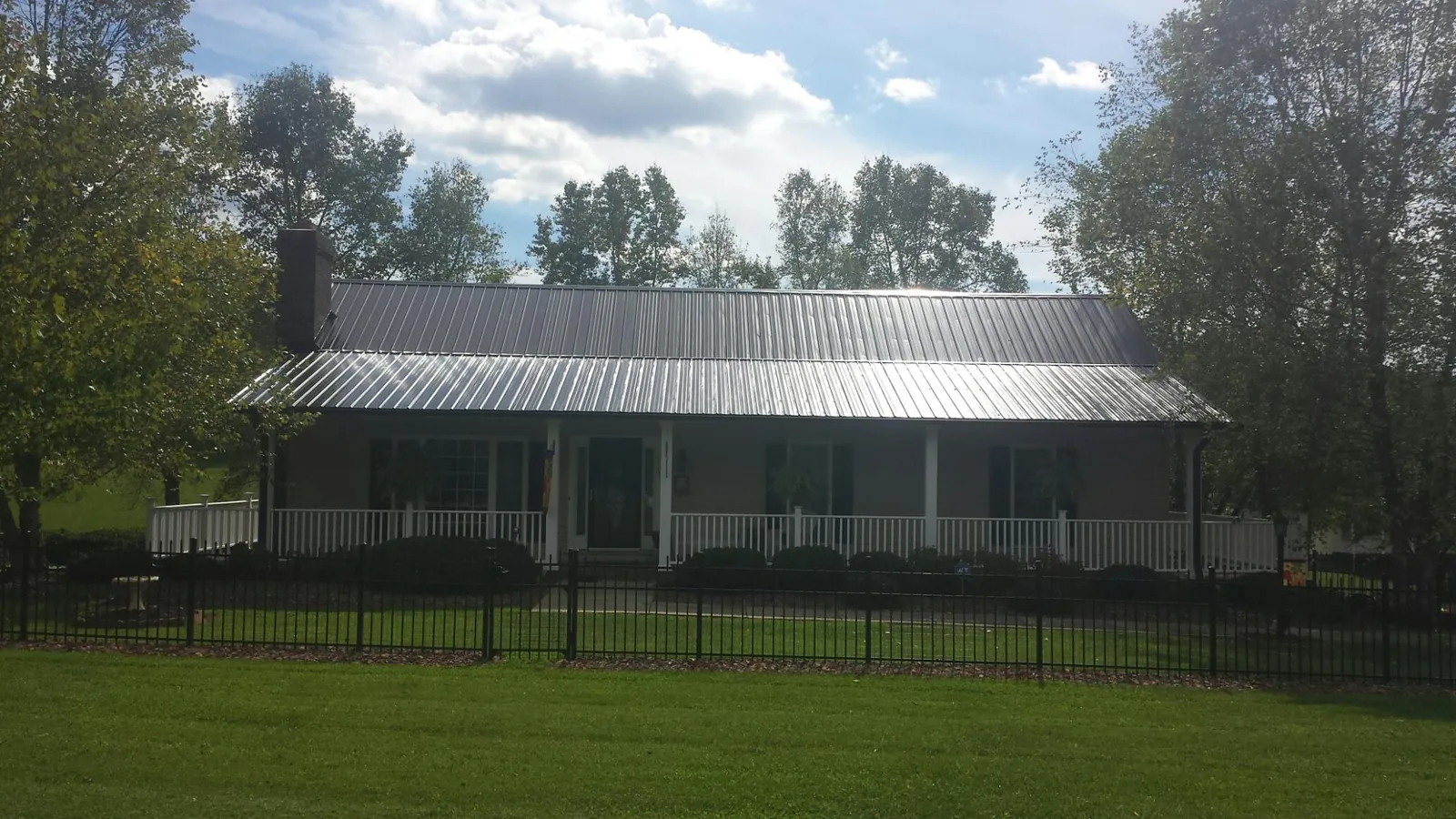 Gray metal roof on a brick ranch with a full width front porch in Blachly