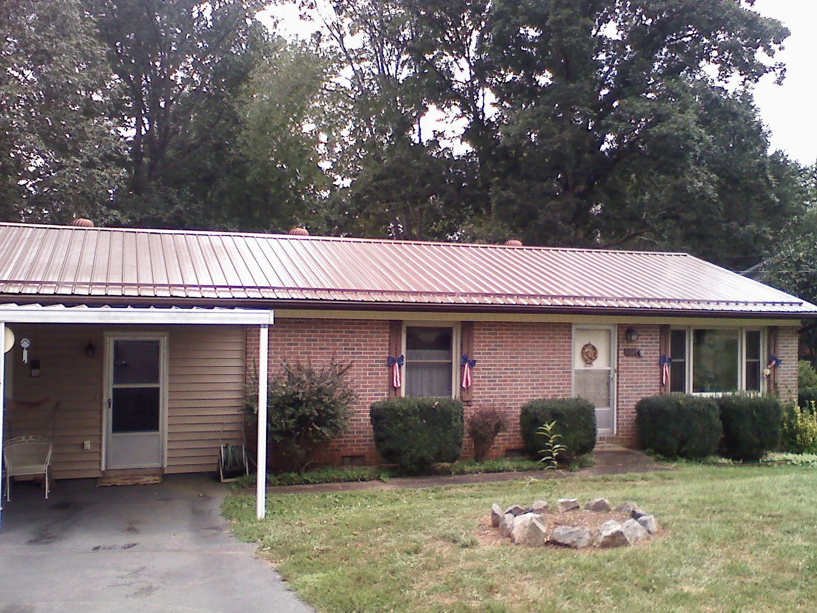 Bronze metal roof and carport on a brick ranch home — Roof Repair work by our crew in Blachly