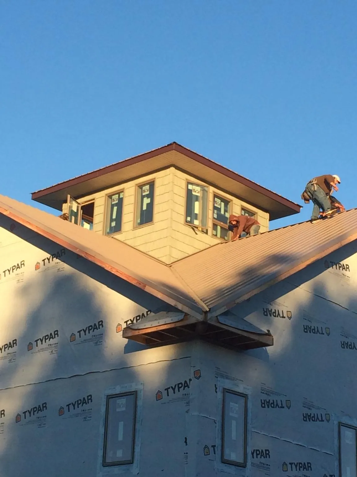 Roofers working around a rooftop cupola on a new metal roof at sunset — Roof Waterproofing in Blachly by Roofing Brothers
